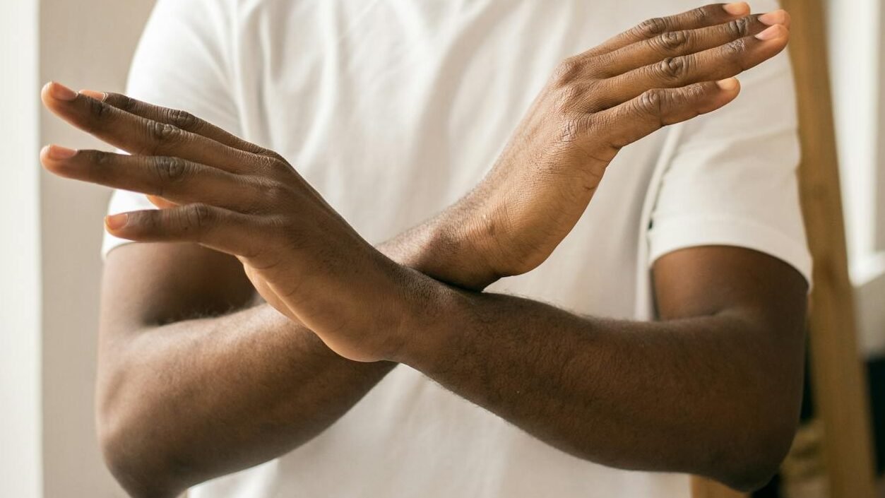 faceless black man showing stop gesture with crossed hands